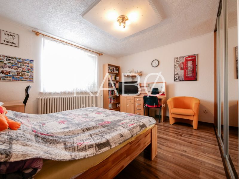 Priestranný 4 izbový rodinný dom po rekonštrukcii - Branč  - Spálňa v rodinnom dome s podlahou s dreveným dekorom, posteľou a pracovným stolom.