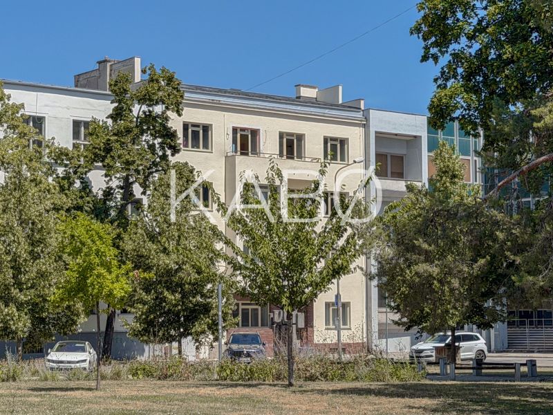Výnimočné bývanie - Mezonet v úplnom centre Nitry  - Budova na ulici Kúpeľná v Nitre, obklopená stromami a zaparkovanými autami.