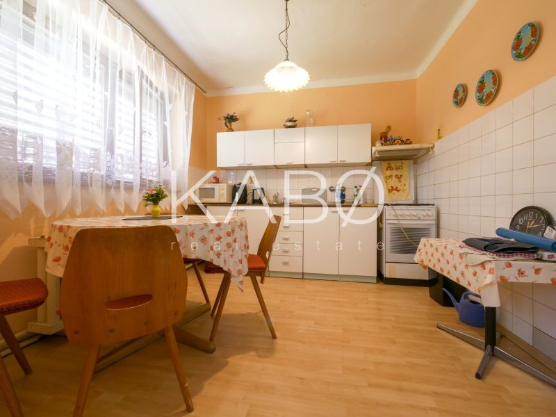 Rodinný dom s krásnym 18 á pozemkom ( stavebným) - Nové Sady  - Kuchyňa v rodinnom dome s podlahou s dreveným dekorom, svetlými závesmi a bielymi skriňami.
