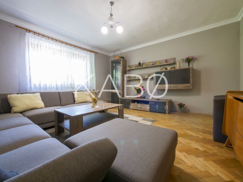 Rodinný dom s krásnym 18 á pozemkom ( stavebným) - Nové Sady  - Obývačka v rodinnom dome s veľkou pohovkou a podlahou s dreveným dekorom.