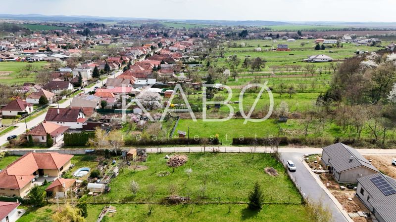 Nádherný pozemok pri lese - 687 m2 - Jelenec - Letecký pohľad na pozemky pre bývanie v Jelenci, obklopené zeleňou a domami.