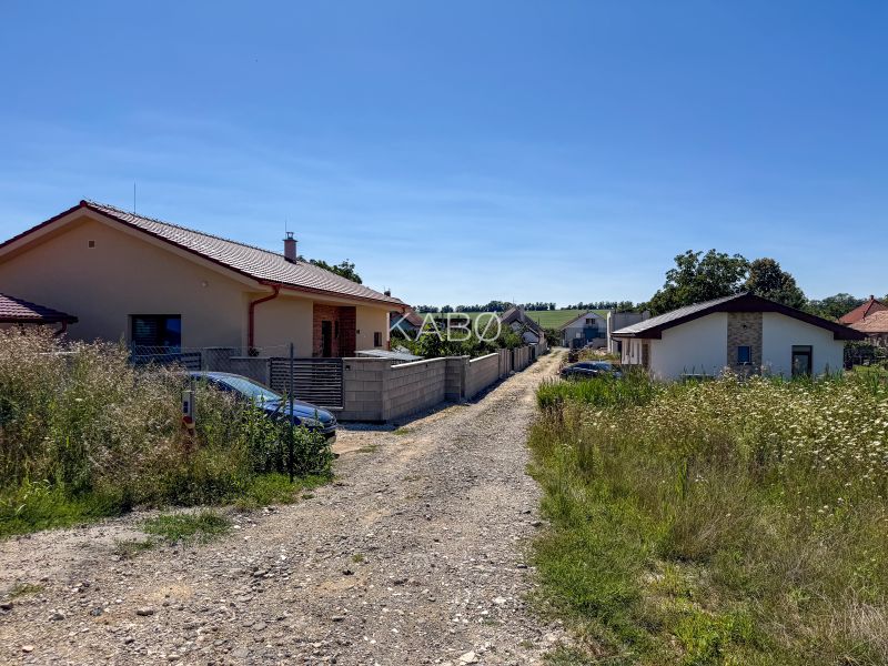 Základová doska na  575 m2 pozemku - Čeľadice  - Čeľadice: Pozemky - bývanie s domami, cestou a parkovanými autami uprostred prírody.