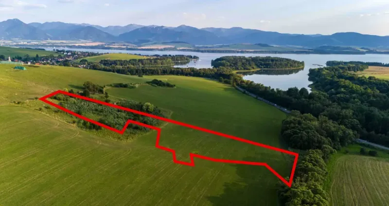 Liptovský Trnovec – 6.488 m2 POZEMOK na MOBILNÝ dom - Letecký pohľad na Zvláštne nehnuteľnosti v Liptovskom Trnovci s okolím a vodnou plochou.