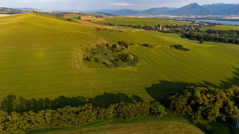 Liptovský Trnovec – 6.488 m2 POZEMOK na MOBILNÝ dom - Rozsiahle zelené polia a kopce v Liptovskom Trnovci, ponúkajúce pohľad na zvláštne nehnuteľnosti.