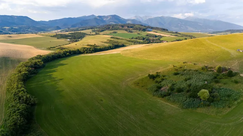 Liptovský Trnovec – 6.488 m2 POZEMOK na MOBILNÝ dom - Pohľad na rozľahlé polia v Liptovskom Trnovci s horami. Zvláštne nehnuteľnosti.