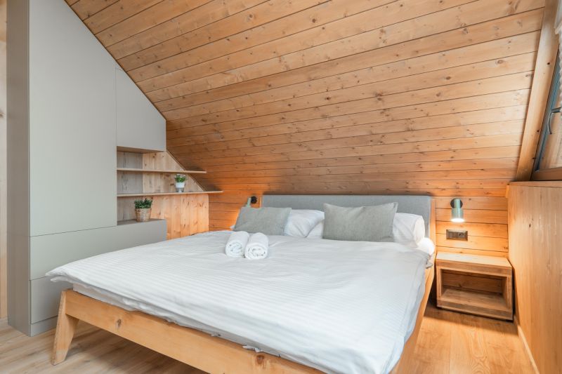 I Luxusné dvojpodlažné chalet pri Liptovskej Mare - Spálňa v Hotely a penzióny s podlahou s dreveným dekorom a šikmým dreveným stropom.