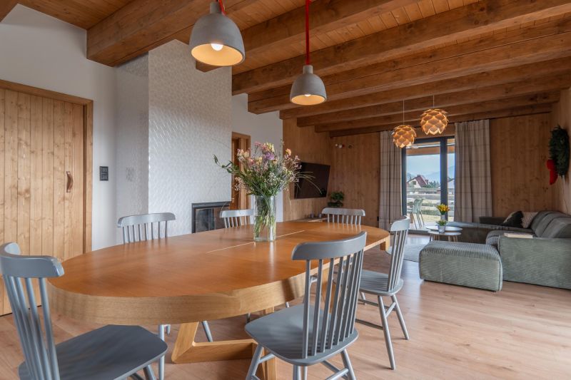 I Luxusné dvojpodlažné chalet pri Liptovskej Mare - Svetlý interiér s drevenými trámami, podlahou s dreveným dekorom a jedálenským stolom. Hotely a penzióny.
