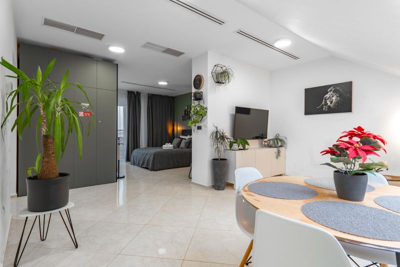 I Exkluzívny penthouse s terasou v absolútnom centre mesta - Obývacia časť 2-izbového bytu s rastlinami, jedálňou a vstupom do spálne.