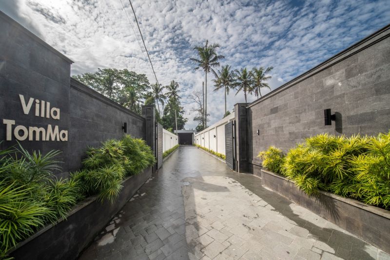 I Na predaj Luxusná vila „Tomma“ v Ubud, Bali - Vila v Bali obklopená palmami, dláždená cesta a zeleň pozdĺž plotu.