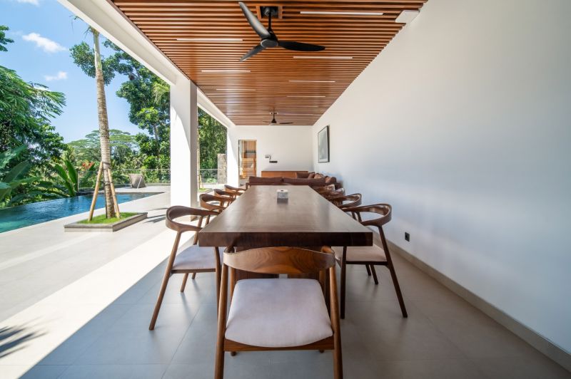 I Na predaj Luxusná vila „Tomma“ v Ubud, Bali - Jedálenský priestor vo vile s výhľadom na bazén a terasu, skombinovaný so stropným ventilátorom.