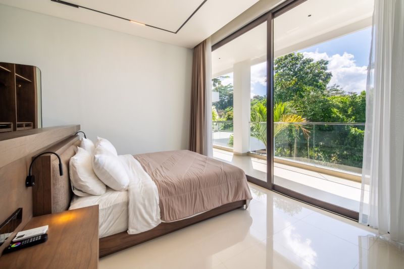 I Na predaj Luxusná vila „Tomma“ v Ubud, Bali - Spálňa vo vile s výhľadom na zeleň, veľké okná a pohodlná posteľ.