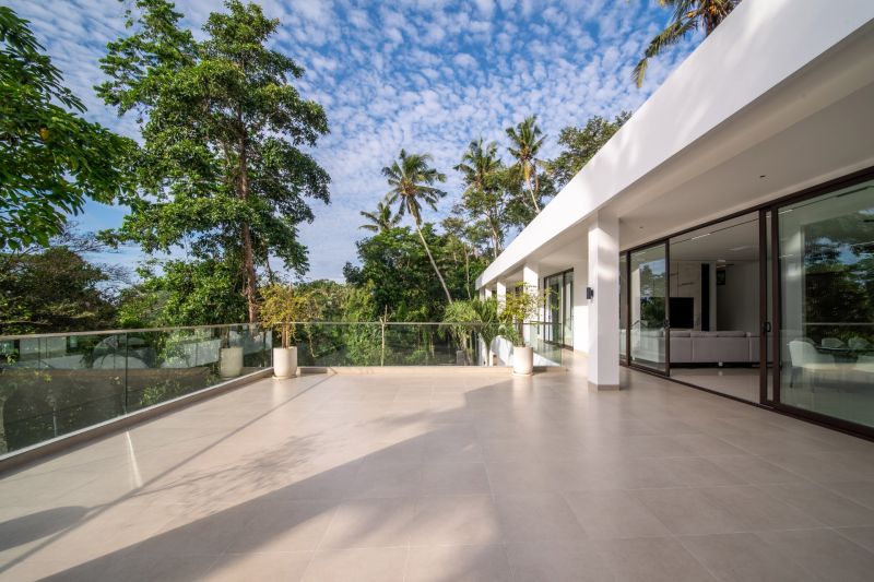 I Na predaj Luxusná vila „Tomma“ v Ubud, Bali - Terasa pri Vile v Bali s výhľadom na zeleň a skleneným zábradlím.