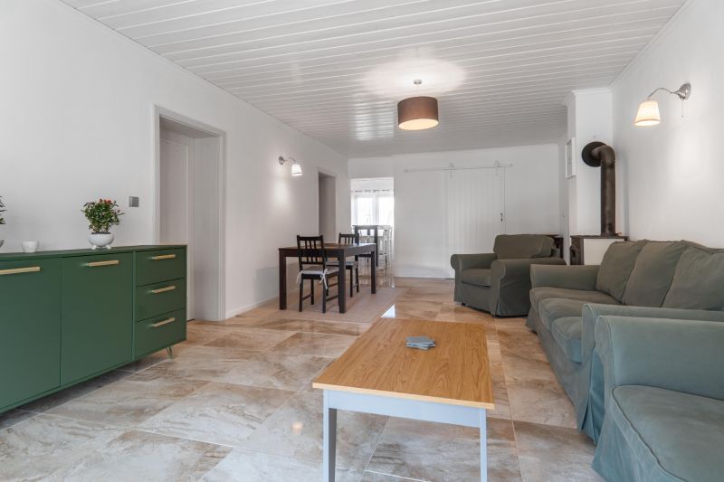 Stavebný pozemok 8 500 m² s podnikateľským potenciálom - Obývacia izba s pohovkou, krbom, jedálenským stolom a podlahou s dreveným dekorom.