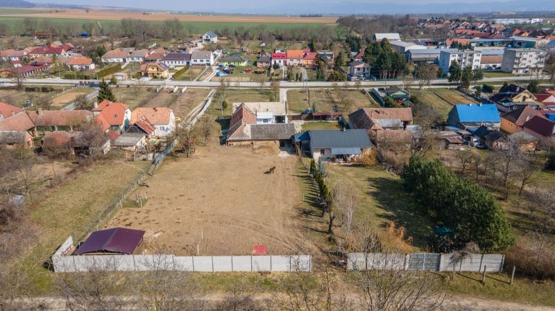 Stavebný pozemok 8 500 m² s podnikateľským potenciálom - Pozemky na bývanie v Dolnom Lopašove, obklopené domami, záhradami a výhľadom na okolie.