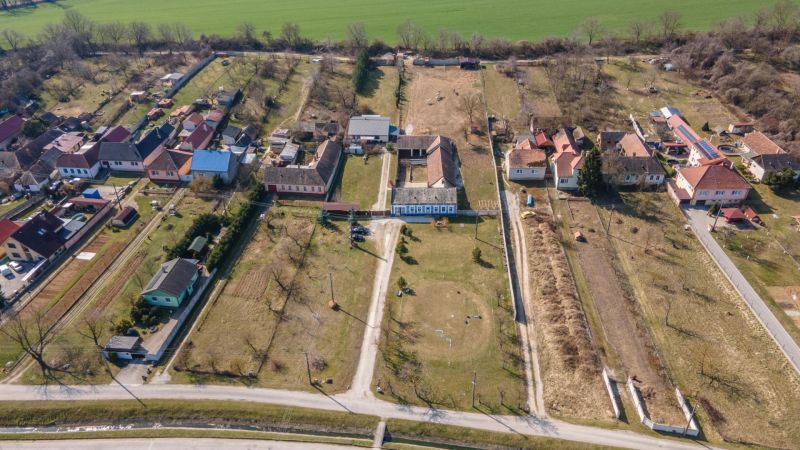 Stavebný pozemok 8 500 m² s podnikateľským potenciálom - Dedinský pohľad na pozemky v Dolnom Lopašove so záhradami a domami na bývanie.