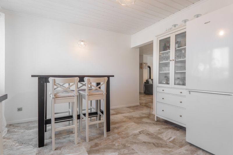 Stavebný pozemok 8 500 m² s podnikateľským potenciálom - Interiér s jedálenským stolom a stoličkami, vedľa biely kuchynský nábytok.