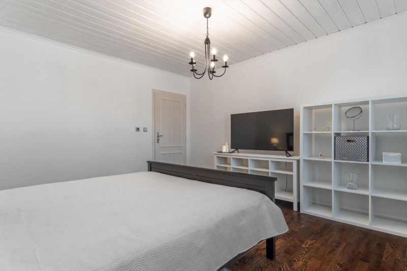 Stavebný pozemok 8 500 m² s podnikateľským potenciálom - Spálňa s lusterom, TV, regálmi a podlahou s dreveným dekorom. Pozemky - bývanie.