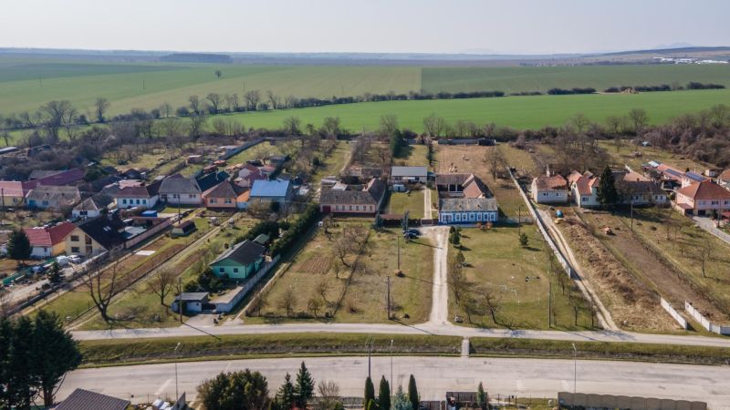 Stavebný pozemok 8 500 m² s podnikateľským potenciálom - Letecká fotografia vidieka v Dolnom Lopašove so záhradami a poľami. Pozemky - bývanie.