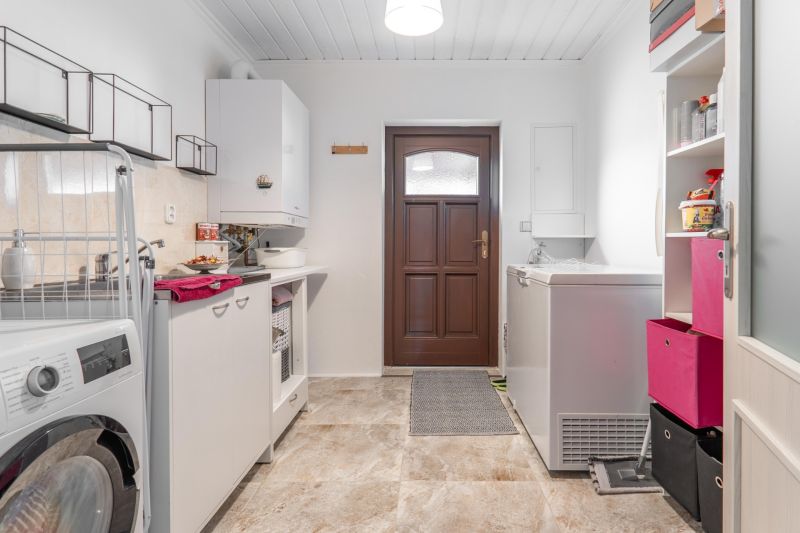 Stavebný pozemok 8 500 m² s podnikateľským potenciálom - Práčovňa s práčkou a úložným priestorom, podlaha s dreveným dekorom, biele steny.