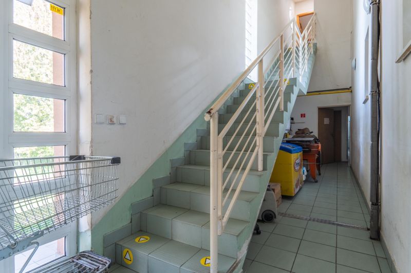 I PREDAJ – FUNGUJÚCA PEKÁREŇ A POTRAVINY V TRNAVE - Schodisko vo výrobných priestoroch so zelenými dlažbami a košíkmi na kolieskach.