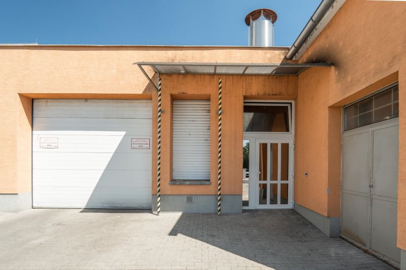 I PREDAJ – FUNGUJÚCA PEKÁREŇ A POTRAVINY V TRNAVE - Výrobné priestory na Koniarekovej ulici v Trnave s oranžovou fasádou a vrátami.