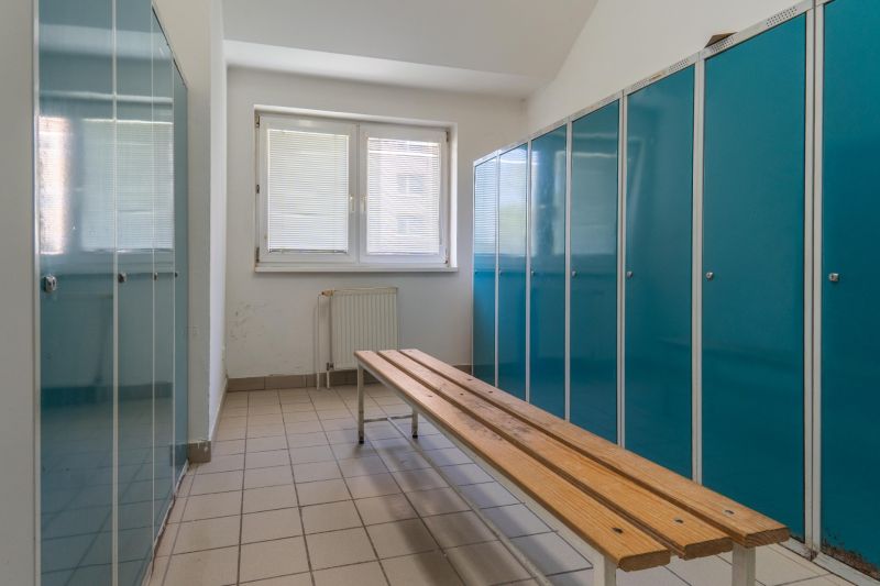 I PREDAJ – FUNGUJÚCA PEKÁREŇ A POTRAVINY V TRNAVE - Kovové skrinky a lavica na dlaždicovej podlahe vo výrobných priestoroch.