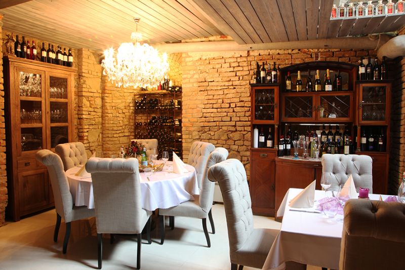 ZNÍŽENÁ CENA! I Predaj komerčného priestoru na ul. Obchodna - Reštauračné obchodné priestory s kamennými stenami a lustrom, elegantne prestreté stoly.