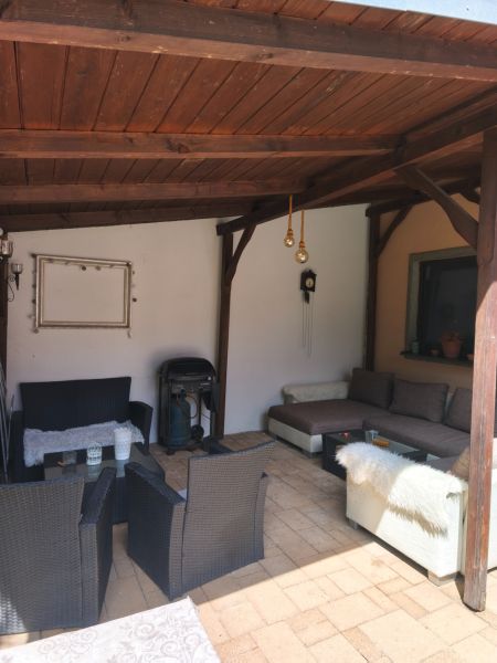 Veľký dom s veľkou garážou v Mankovciach  - Krytá terasa rodinného domu v Mankovciach s ratanovým nábytkom a krbom.