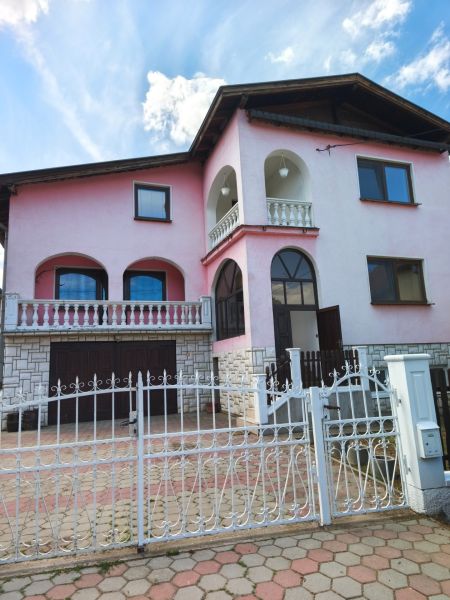 Veľký dom s veľkou garážou v Mankovciach  - Rodinný dom v Mankovciach s ružovou fasádou, poschodím a kovaným plotom.