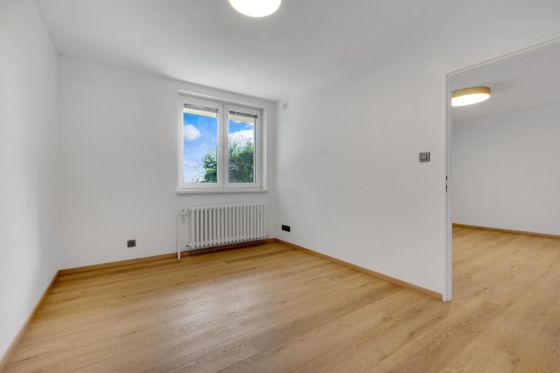 ,Prenájom moderný 3 izb. byt, Sološnícka ul,124 m2, Karlova Ves - Prázdna izba s podlahou s dreveným dekorom v rodinnom dome, biele steny a okno.
