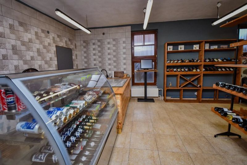 I Dom s wellness, bazénom a hotovým biznis potenciálom - Obchodný interiér s chladiacim pultom a regálmi na víno v rodinnom dome.