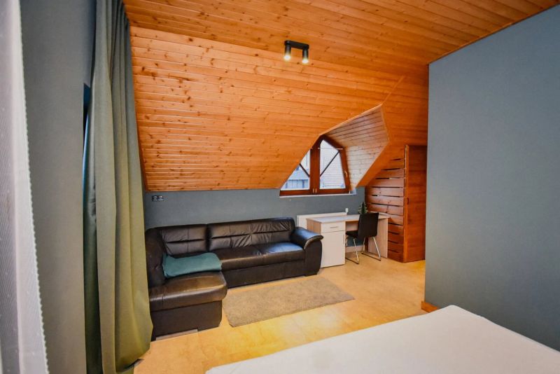 I Dom s wellness, bazénom a hotovým biznis potenciálom - Podkrovná izba v rodinnom dome s koženou sedačkou a písacím stolom.