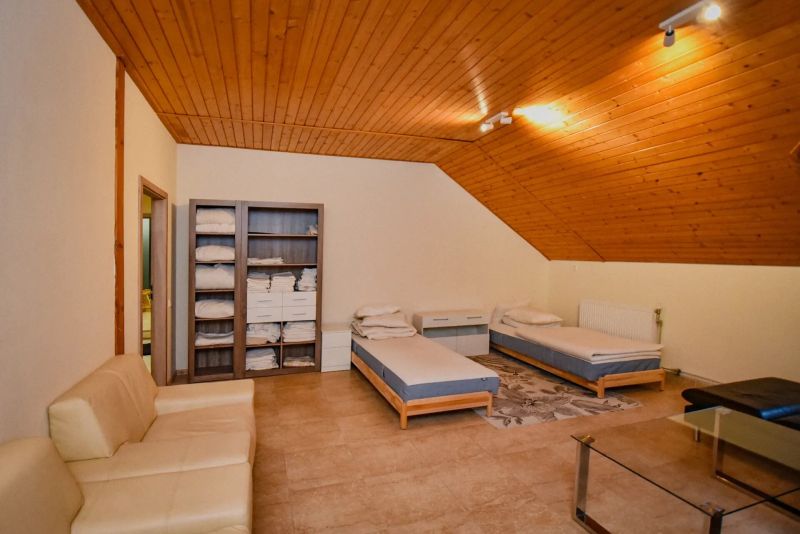 I Dom s wellness, bazénom a hotovým biznis potenciálom - Podkrovná izba rodinného domu s dvoma posteľami, sedačkou a policovou skriňou.