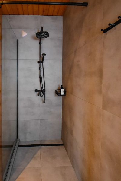 I Dom s wellness, bazénom a hotovým biznis potenciálom - Sprchový kút v rodinnom dome s tmavou dlažbou a dreveným stropom.