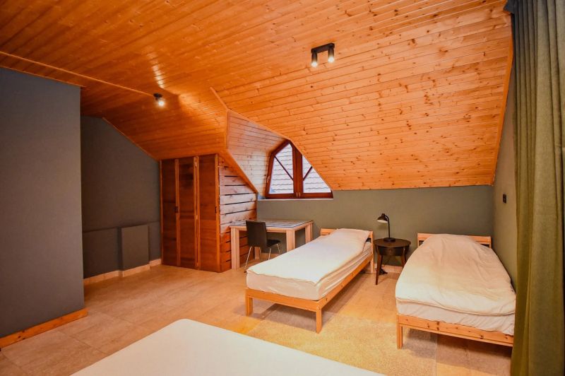 I Dom s wellness, bazénom a hotovým biznis potenciálom - Podkrovná izba v rodinnom dome s dvoma posteľami a dreveným obkladom stropu.