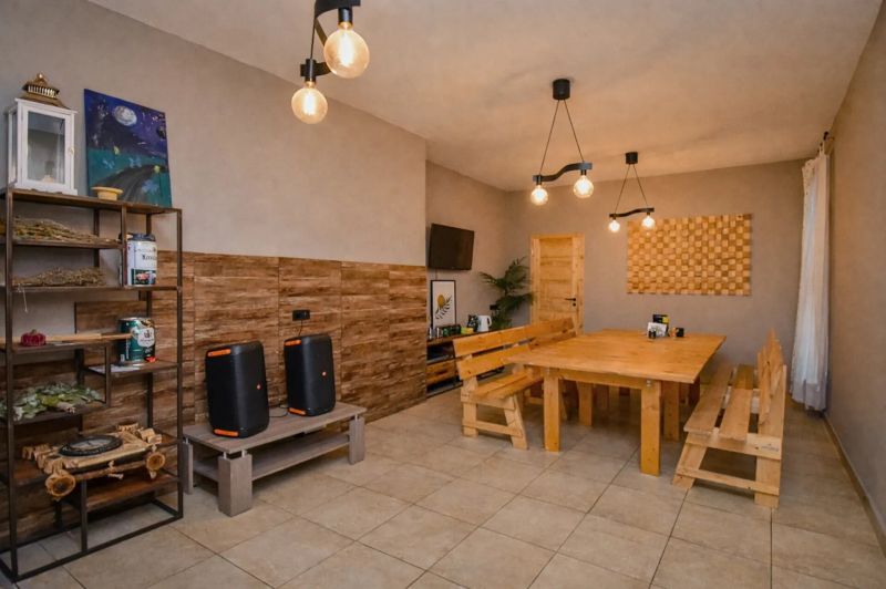 I Dom s wellness, bazénom a hotovým biznis potenciálom - Jedáleň v rodinnom dome s dreveným stolom a lavicami, dekorácie na stenách.