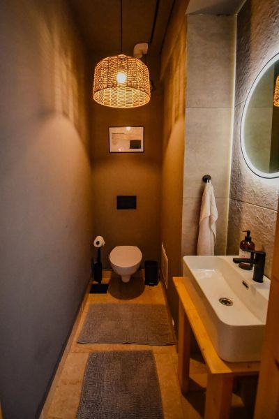 I Dom s wellness, bazénom a hotovým biznis potenciálom - Malá kúpeľňa s toaletou, umývadlom, nástennými svietidlami a dekoráciou v rodinnom dome.