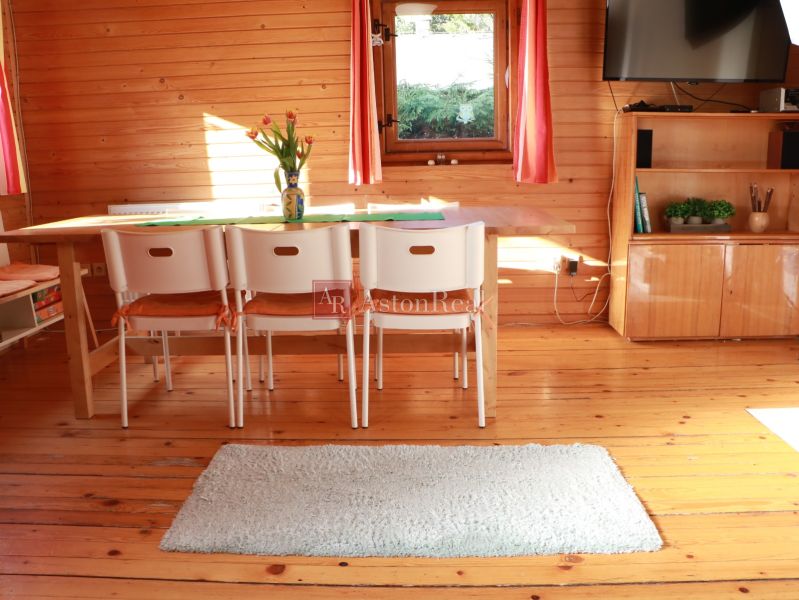 Chalupa Tále, okr.Brezno, pozemok 680m2,  - Drevený interiér chaty s jedálenským stolom, bielymi stoličkami a podlahou s dreveným dekorom.