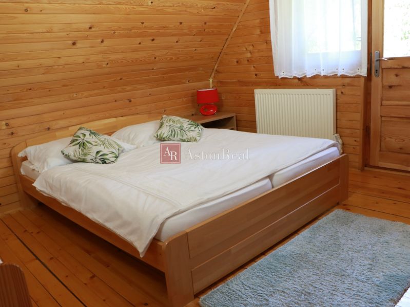 Chalupa Tále, okr.Brezno, pozemok 680m2,  - Spálňa v chate s dreveným obkladom, posteľou a podlahou s dreveným dekorom.