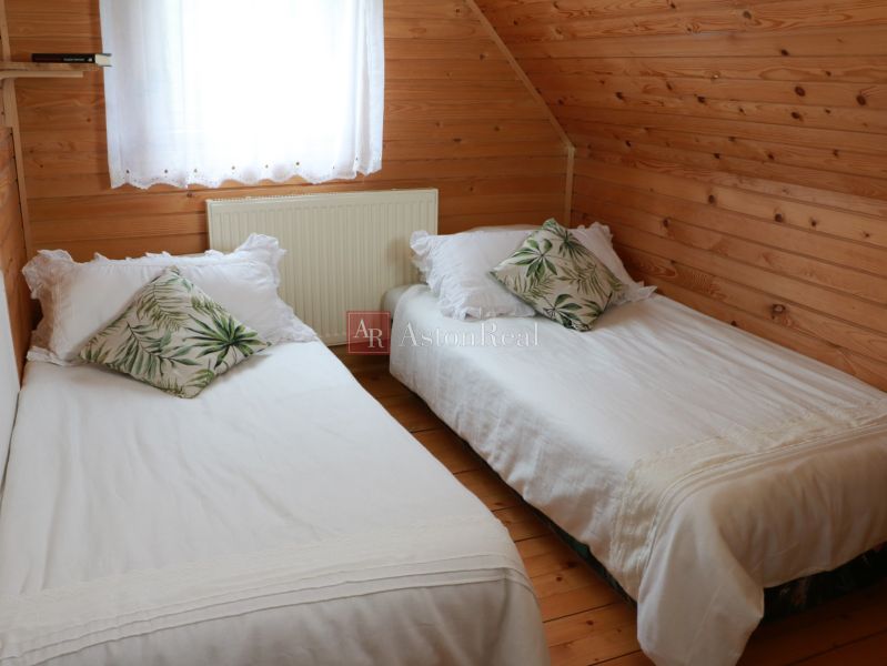 Chalupa Tále, okr.Brezno, pozemok 680m2,  - Spálňa chaty s dreveným obkladom, dvoma posteľami a dekoratívnymi vankúšmi.