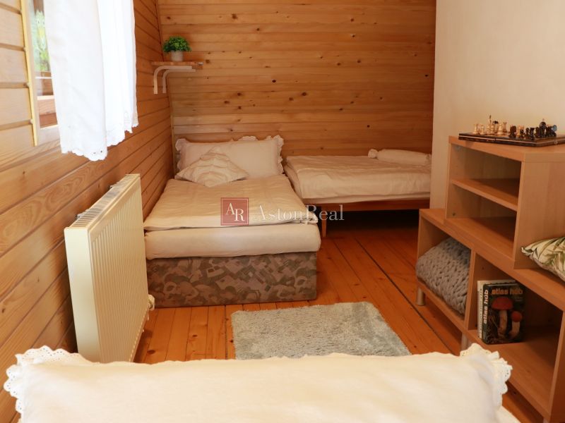 Chalupa Tále, okr.Brezno, pozemok 680m2,  - Drevené obloženie izby v chate, dve postele, podlaha s dreveným dekorom, knižnica.