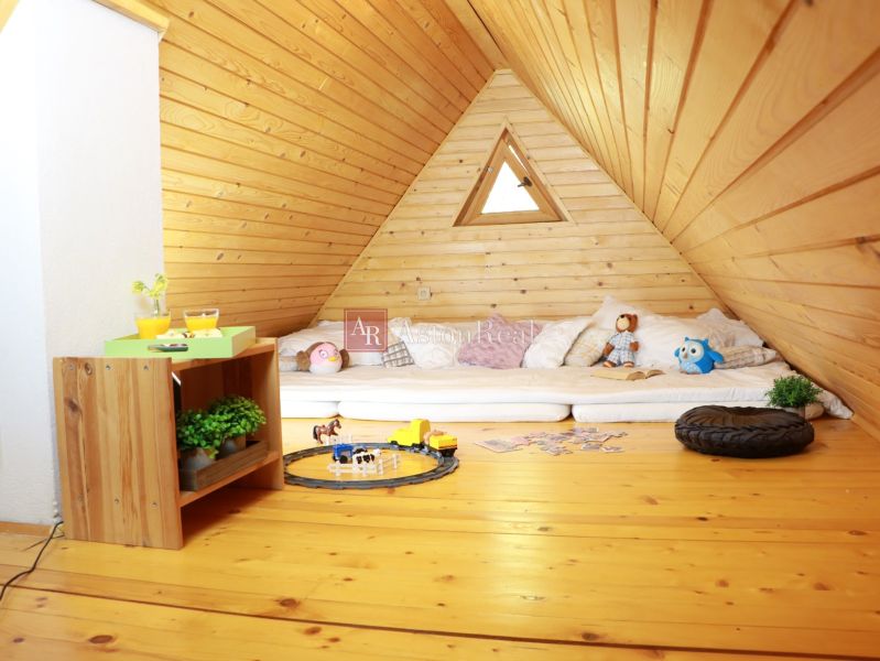Chalupa Tále, okr.Brezno, pozemok 680m2,  - Podkrovný priestor chaty s podlahou s dreveným dekorom obsahuje matrace, hračky a stolík.