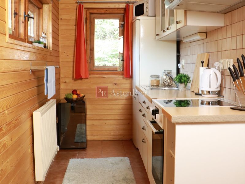 Chalupa Tále, okr.Brezno, pozemok 680m2,  - Kuchyňa v chate s dreveným dekorom, bielymi spotrebičmi a oknom s výhľadom.