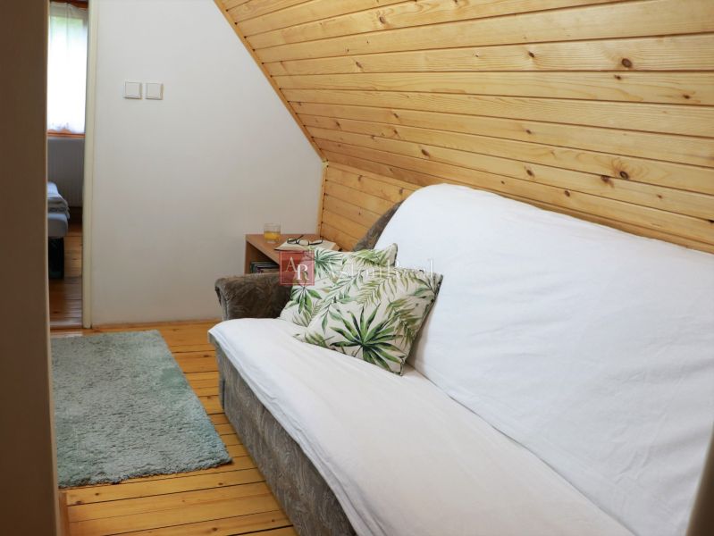 Chalupa Tále, okr.Brezno, pozemok 680m2,  - Pohodlný gauč s dekoračným vankúšom v útulnej chate s drevenými dekoráciami.