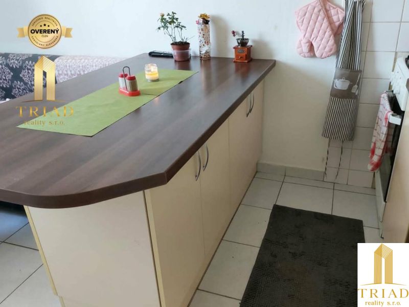 Predaj 1 izbový byt Nové Zámky - Kuchynská linka s ostrovčekom v 1-izbovom byte, biela dlažba a dekorácie.
