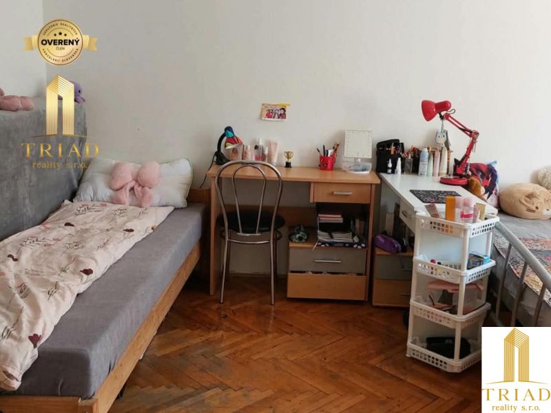 Predaj 1 izbový byt Nové Zámky - Študentská izba v 1-izbovom byte s podlahou s dreveným dekorom a jednoduchým nábytkom.
