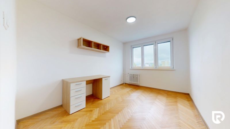 Pekný zariadený 3-izb. byt so šatníkom I Ružinov I - Priestranná izba v 3-izbovom byte s písacím stolom a podlahou s dreveným dekorom.