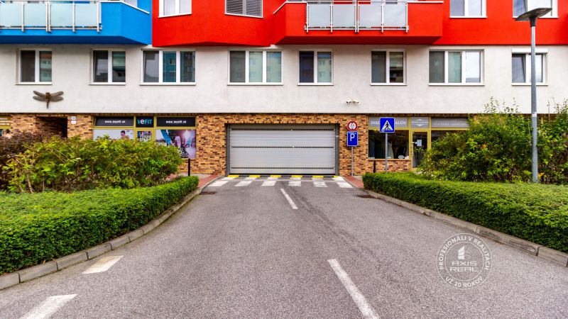 UZAMYKATEĽNÁ GARÁŽ 20m2 v NOVOSTAVBE Vodotika, Lužná ul. - Garáže na Lužnej ulici v Bratislave-Petržalke, obklopené zeleňou a budovami.