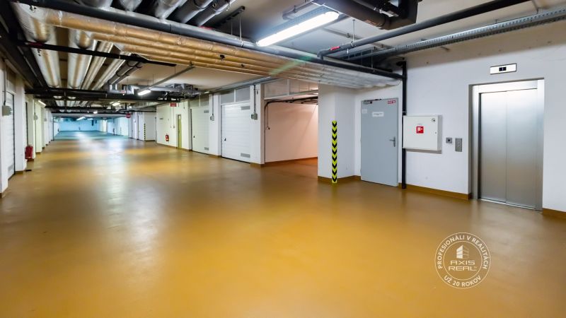 UZAMYKATEĽNÁ GARÁŽ 20m2 v NOVOSTAVBE Vodotika, Lužná ul. - Podzemné garáže s výťahom a oranžovou podlahou, potrubia na strope.
