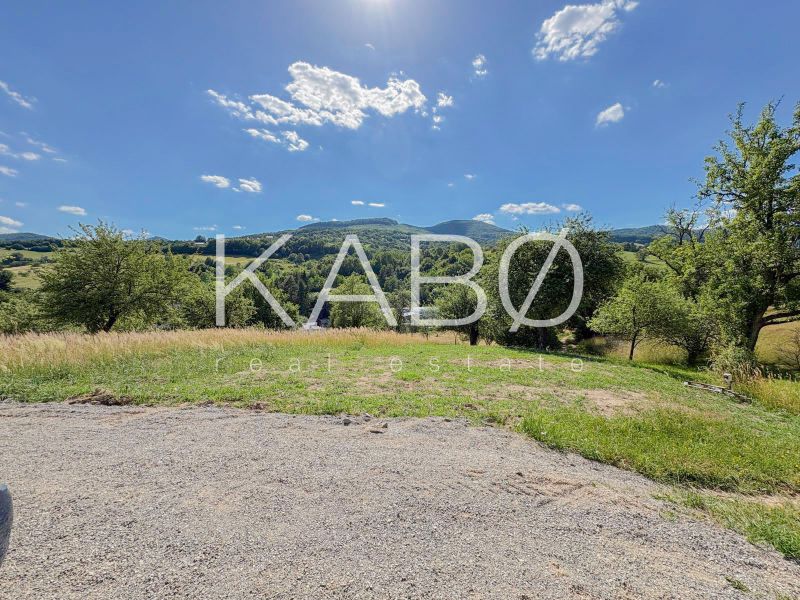 Ideálny Stavebný pozemok 1 353 m² pri Tajchu s krásnymi výhľadmi - Pozemky - bývanie v Novej Bani obkolesené prírodou, lúkami a stromami pod modrou oblohou.